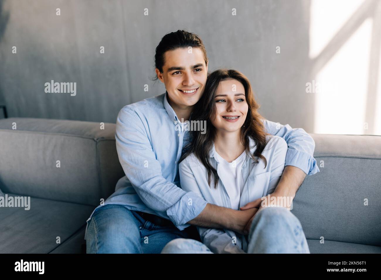 Portrait of young couple in love posing photo shooting seated on couch ...