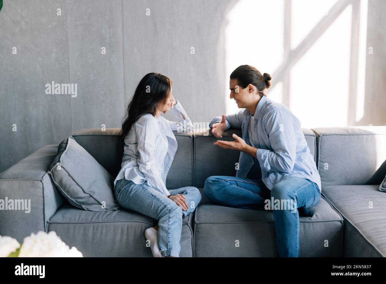Man and young woman sitting on a couch and talk. Stock Photo