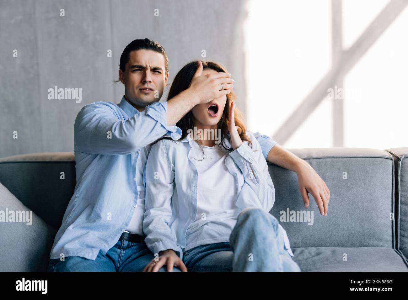 Close-up of a young man surprising woman in the living room at home Stock Photo