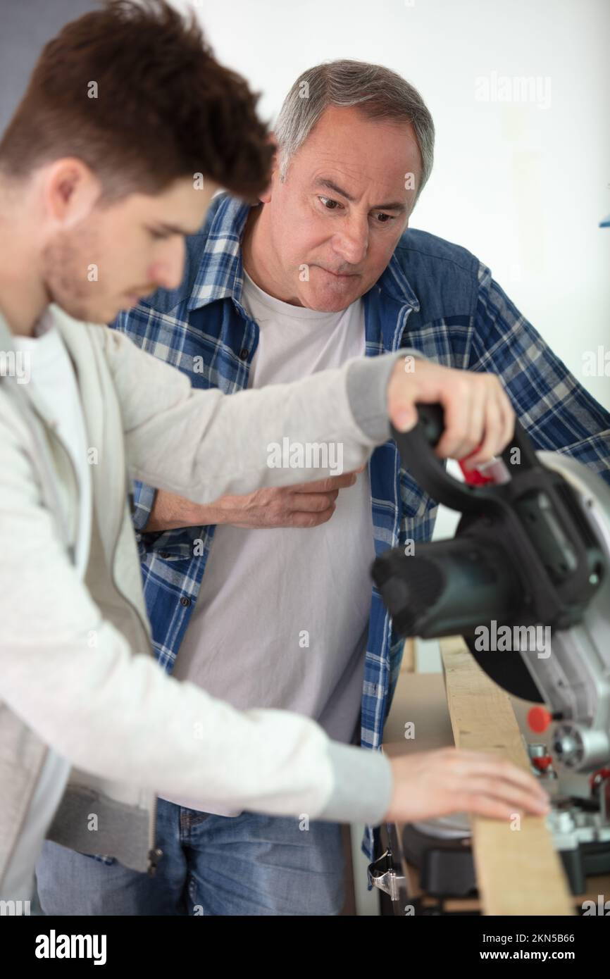 student and teacher in carpentry class using circular saw Stock Photo