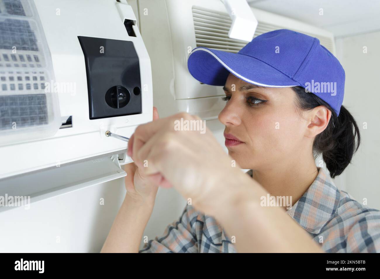 dark haired female electrician installing ac Stock Photo