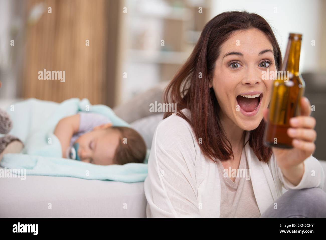 mother drinking beer in front of sleeping baby Stock Photo - Alamy