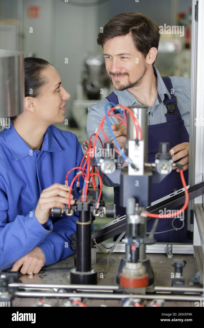 engineer and apprentice working on machine in factory Stock Photo