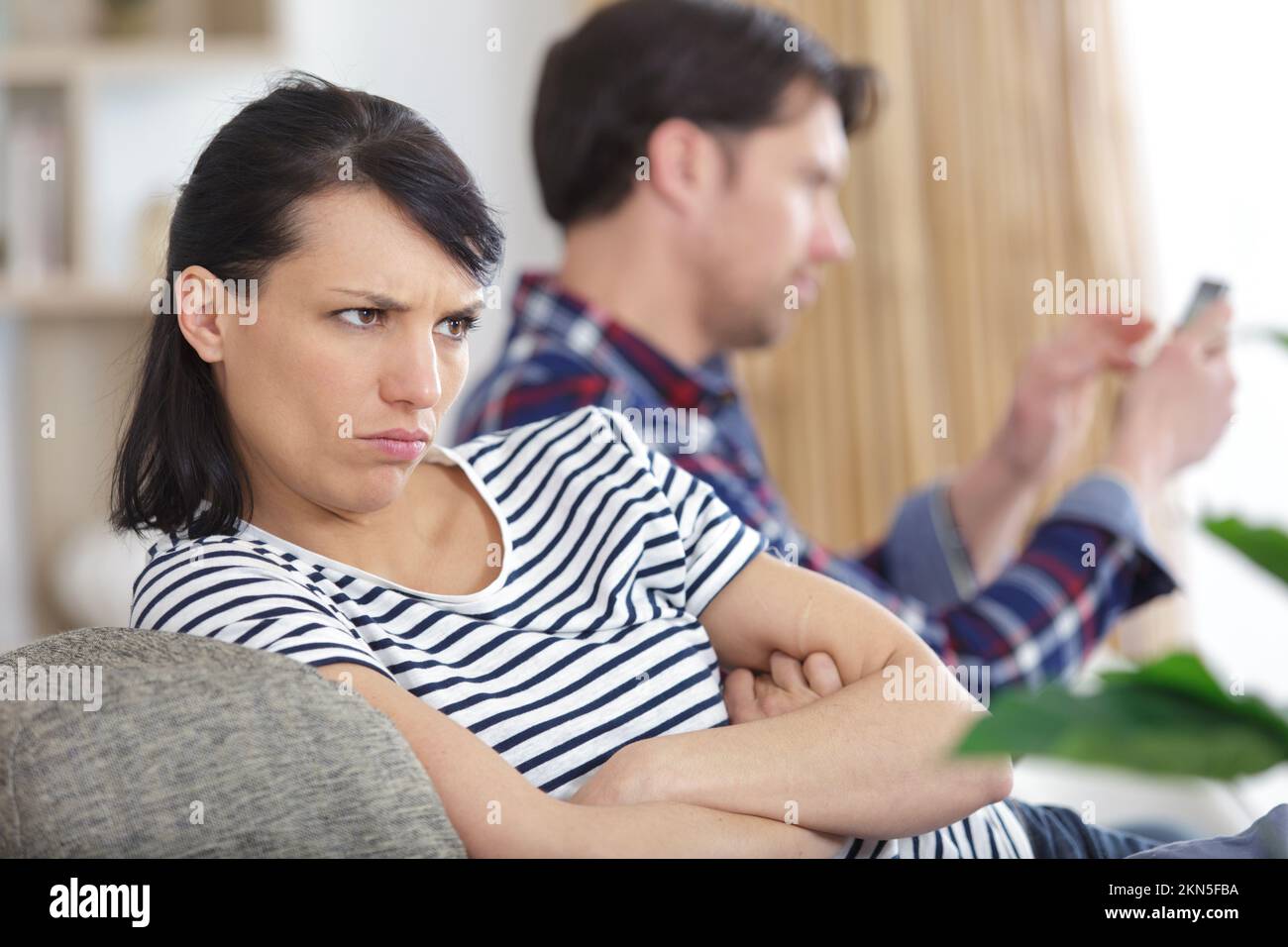 couple sat on the sofa woman is sulking Stock Photo