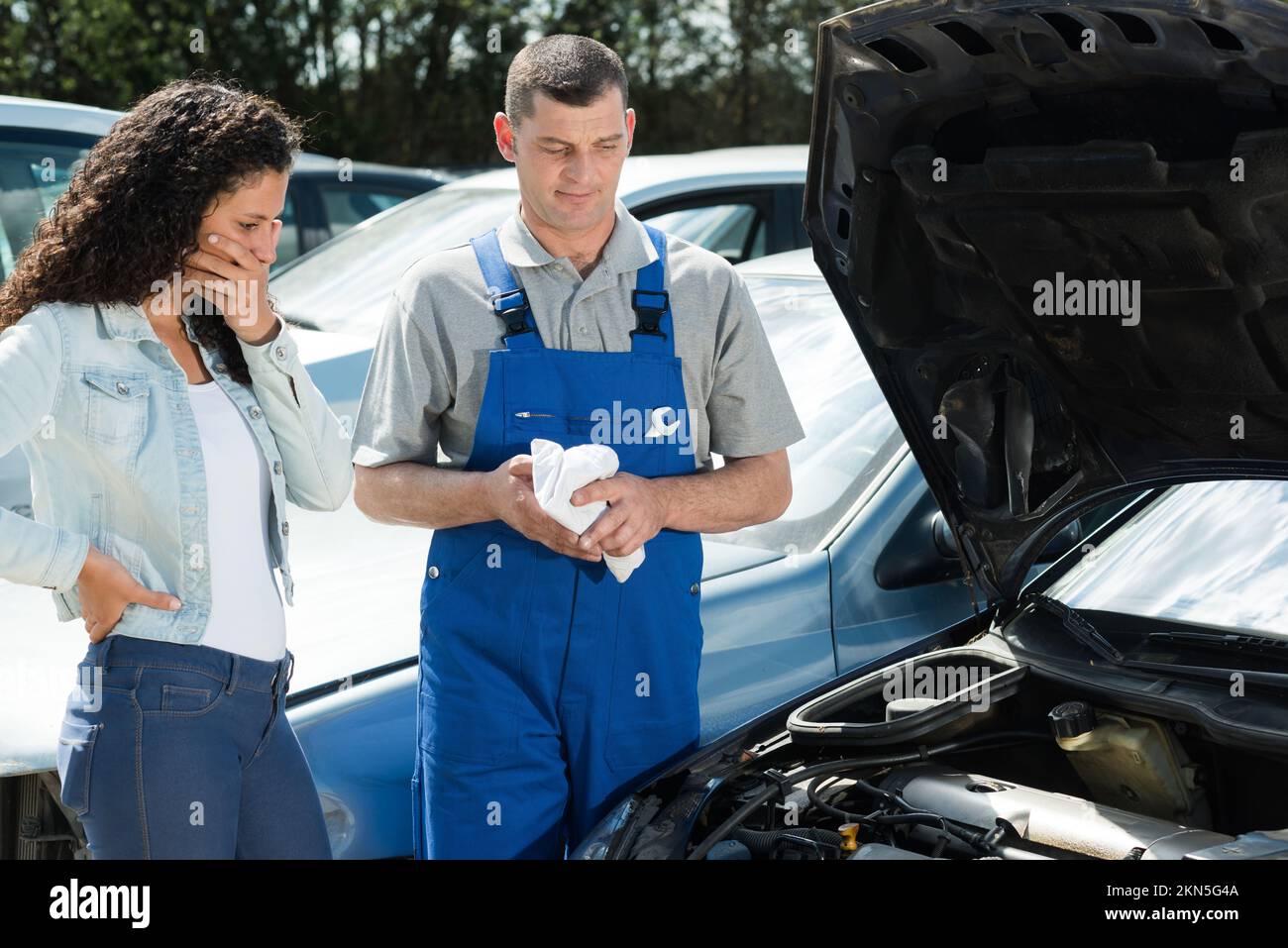 mechanic man and woman examine a car outdoors Stock Photo - Alamy