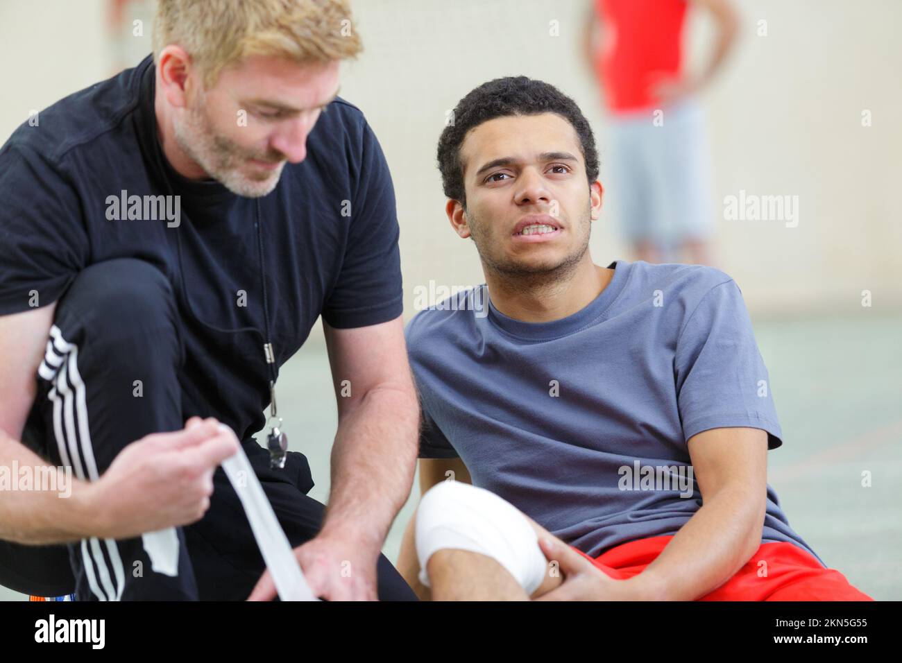 injured football player lying on the ground with coach Stock Photo Alamy