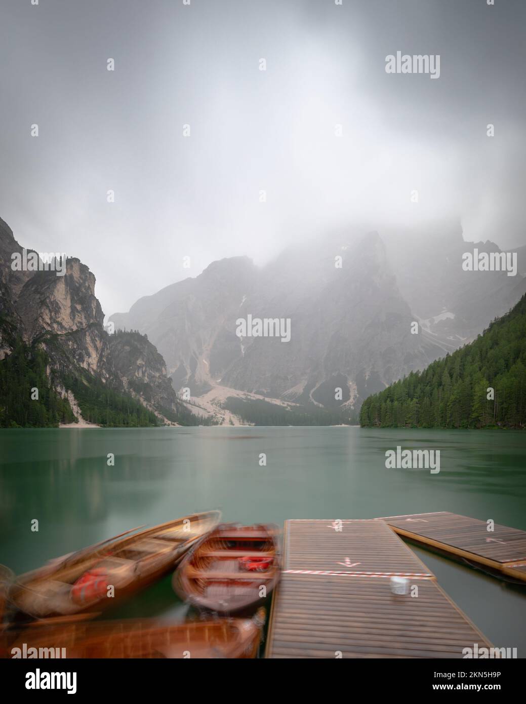 A vertical shot of parked boats by a pier in a lake with the background ...