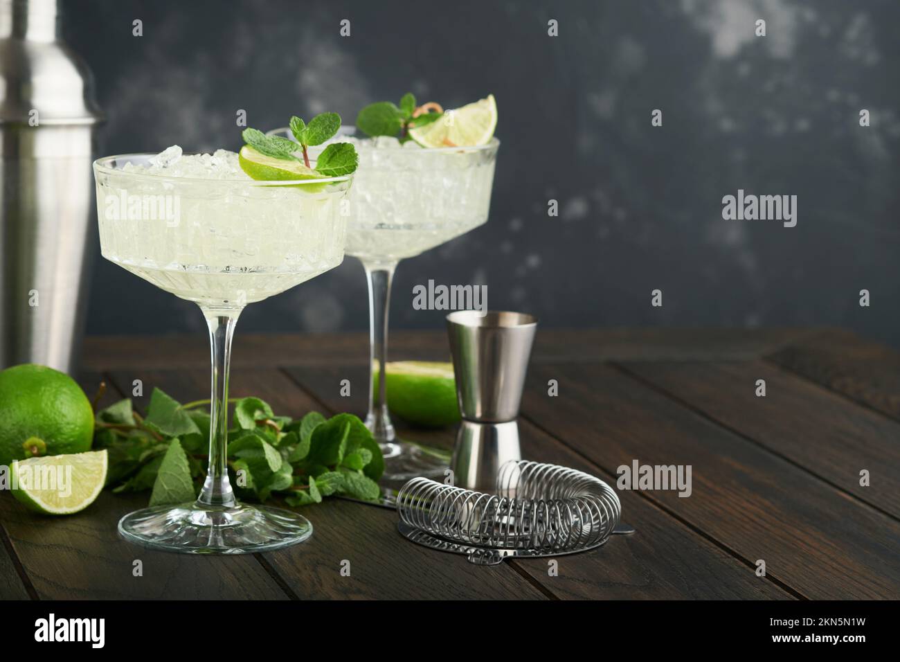Margarita cocktail with lime, tequila, mint and ice on dark table with