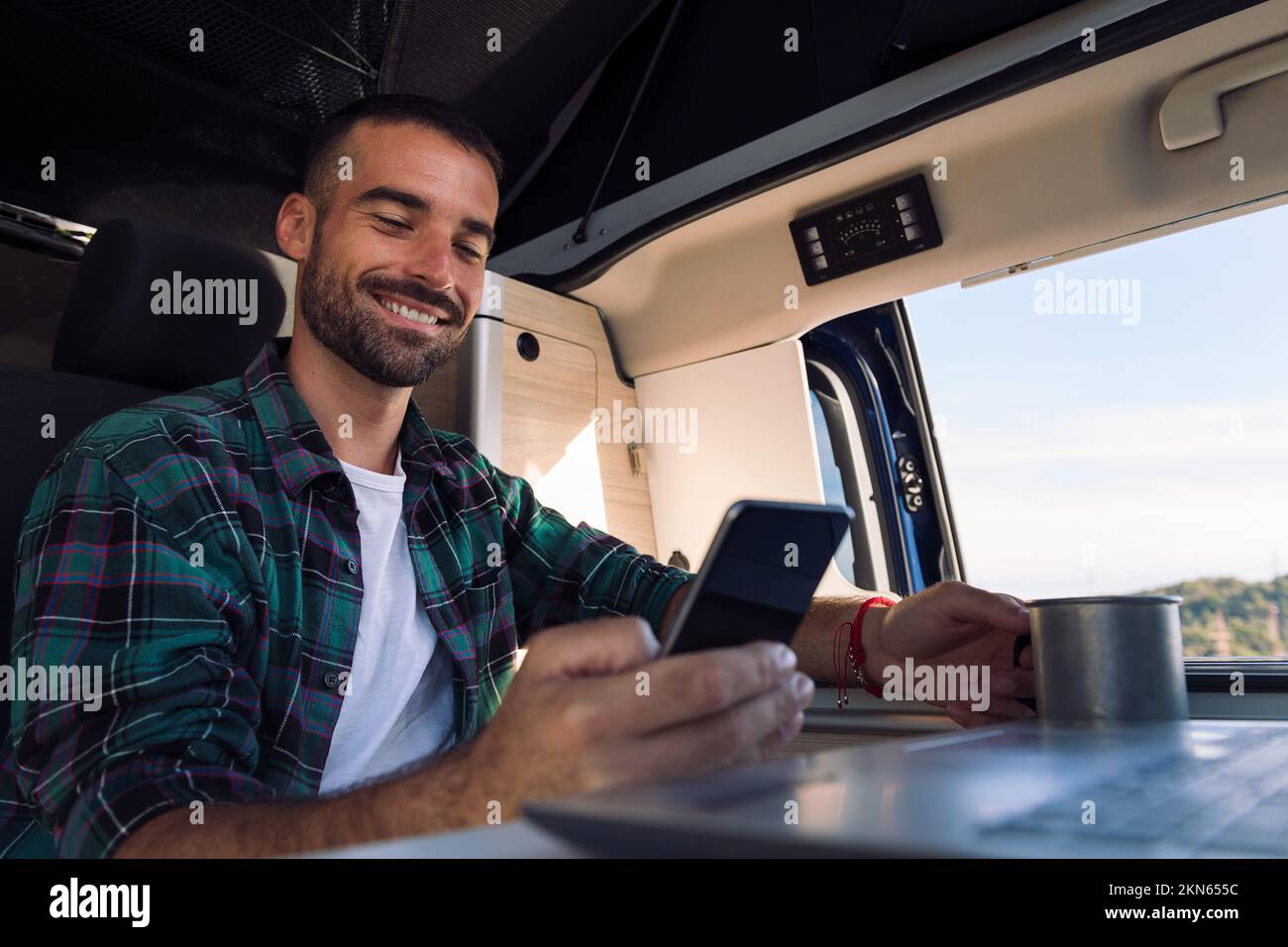 man using mobile phone and laptop from his camper Stock Photo