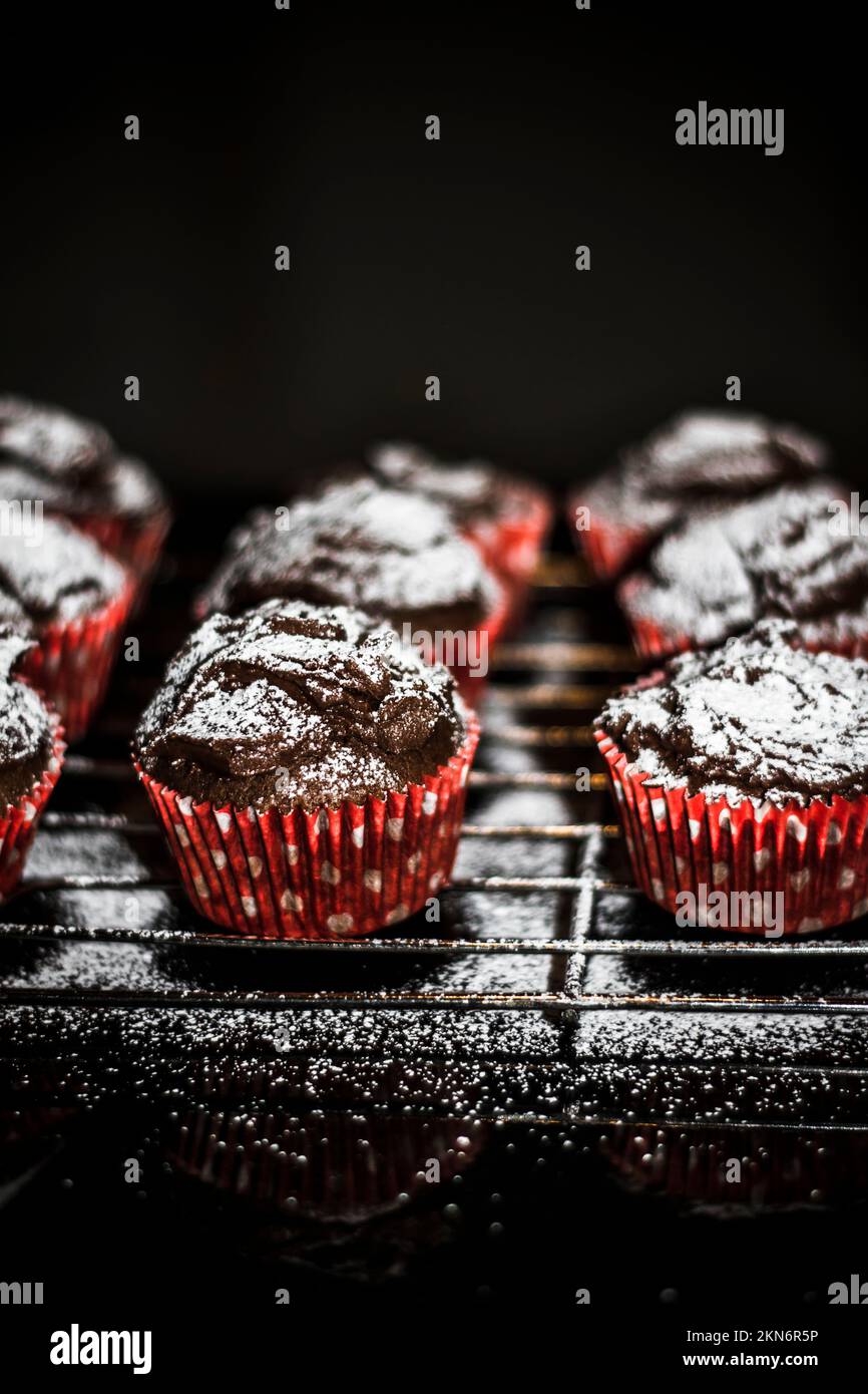 Vertical baked cupcake tray with sprinkles of sugary sweetness on black kitchen bench. Home made desserts Stock Photo