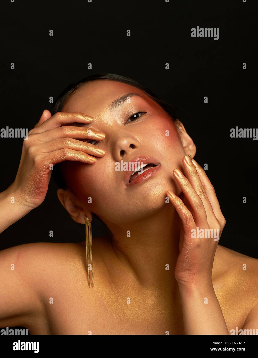An Asian girl on a black background in the studio. Gold. The emotion of fatigue and disappointment Stock Photo