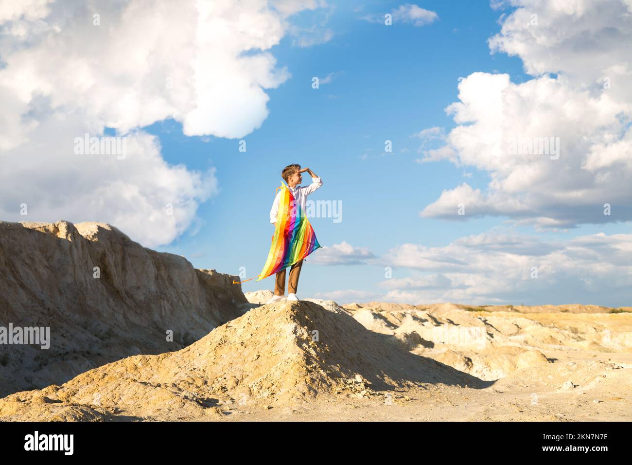 A 9 year old boy holds a bright big kite high above his head. Stock Photo