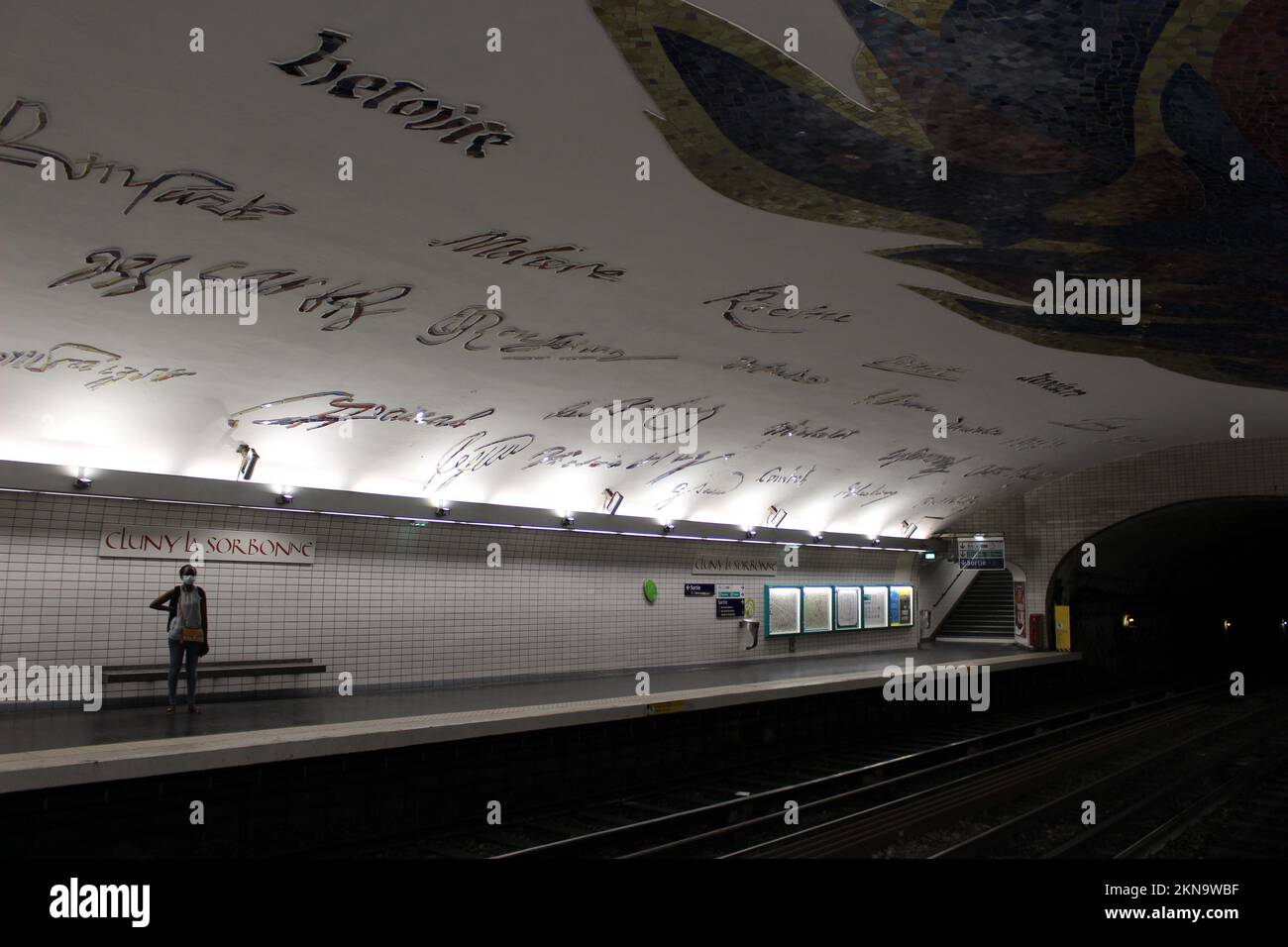 One person standing, waiting alone at a underground metro station in Paris for the train to come - Cluny–La Sorbonne station Stock Photo