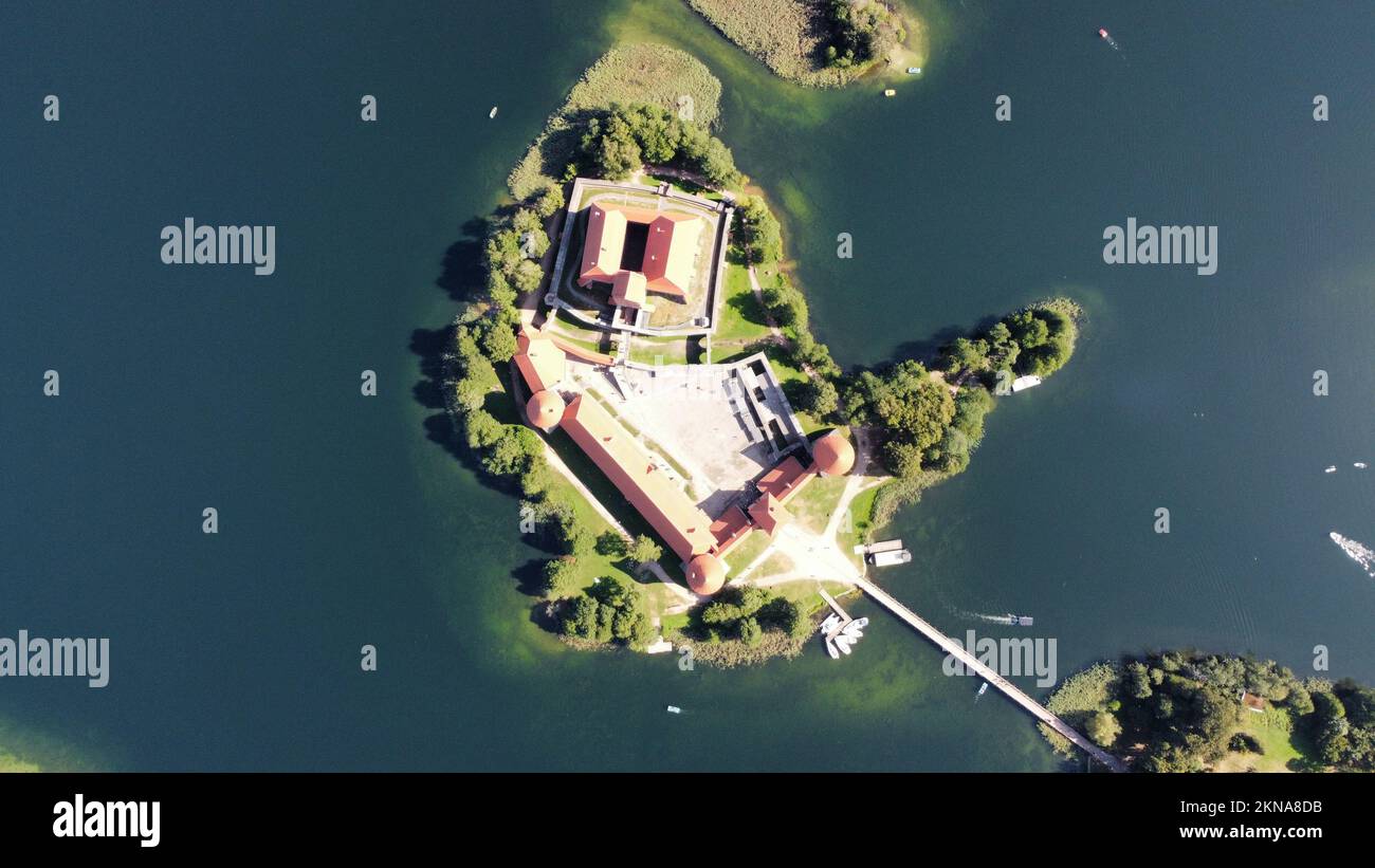 An aerial shot of Trakai Island Castle surrounded by green trees in the heart of Lake Galva Stock Photo