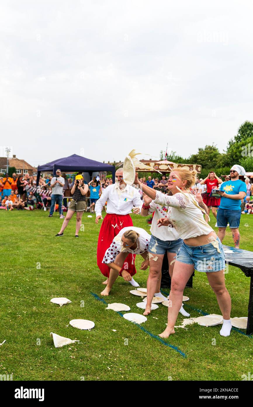 A team of four Ukrainians, throwing custard pies from a table outdoors during the World Custard Pie Championships at Maidstone, England Stock Photo