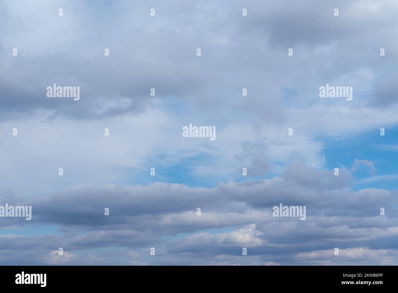 Lots of cumulus clouds far on horizon on blue daylight sky. Light blue sky with clouds, fresh atmosphere. White fluffy clouds running across a sunny b Stock Photo