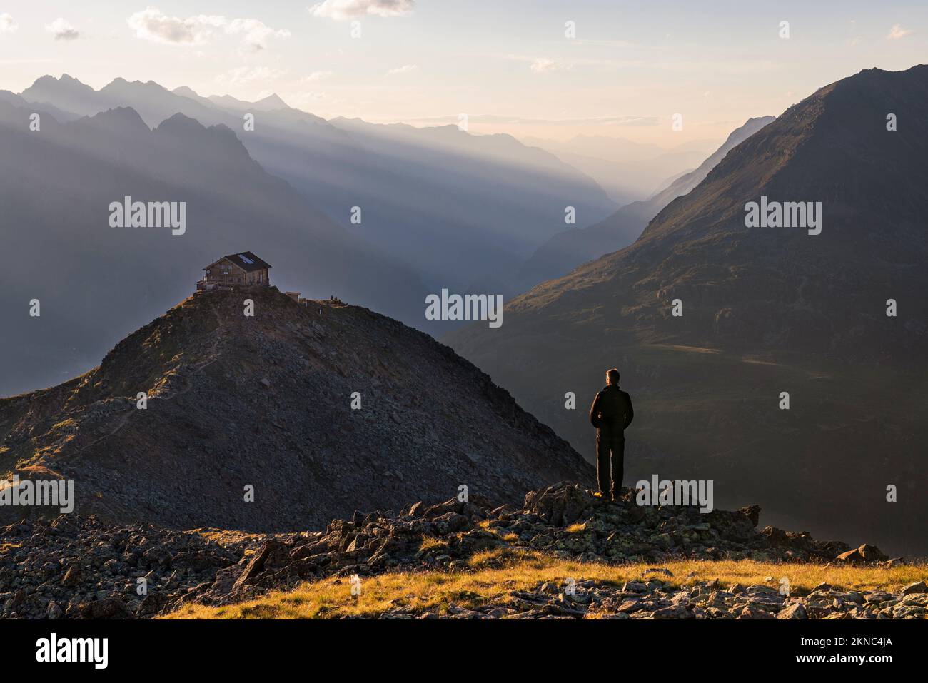 A male hiker watches the sunset over the Brunnenkogelhaus alpine mountain hut above Sölden in the Ötztal Alps, Tyrol, Austria Stock Photo