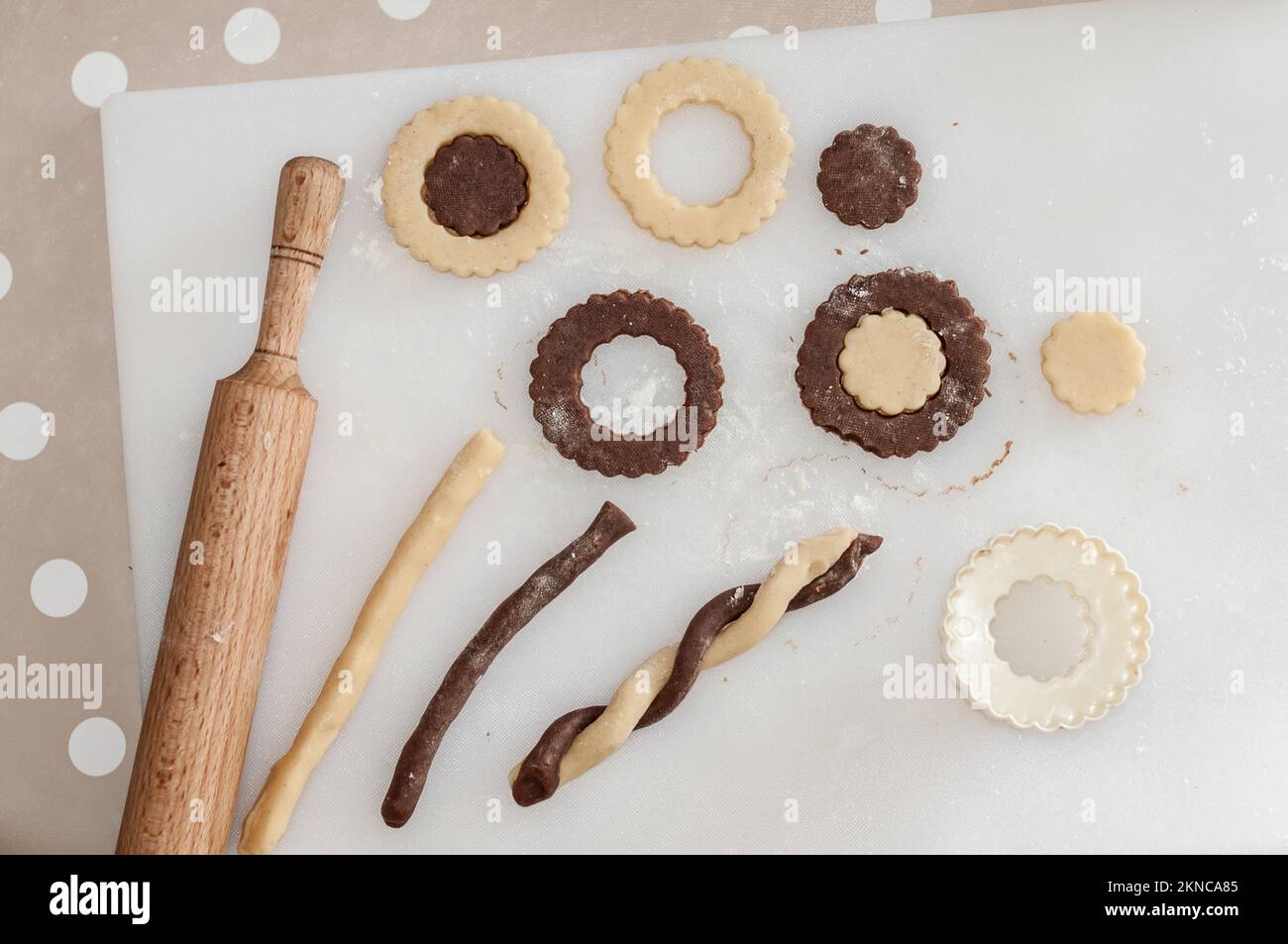 A rolling pin, a cookie cutter, a cutting board with a raw sand dough