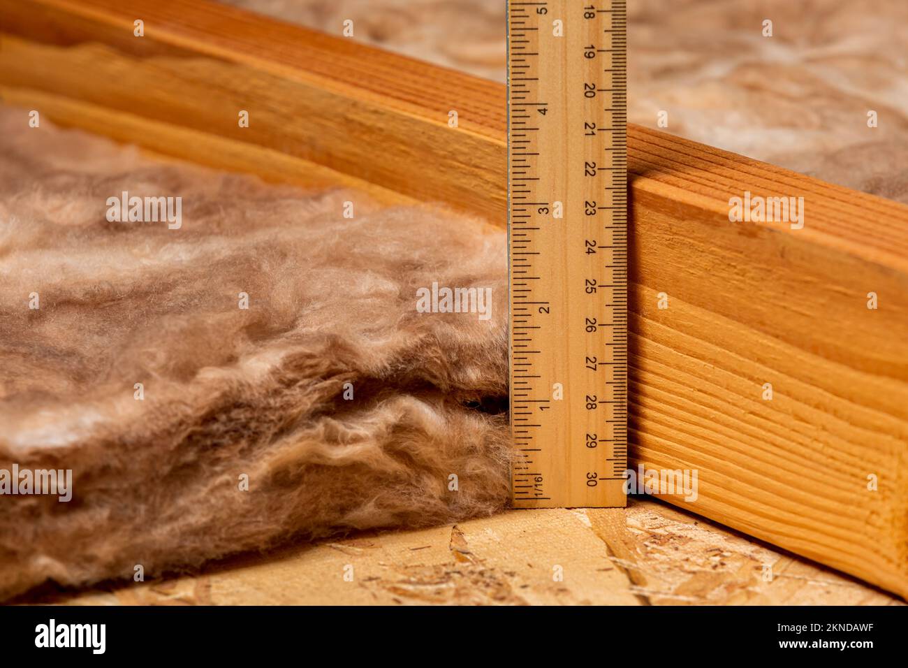 Measuring fiberglass insulation in attic of house with ruler. Home energy savings, heating and cooling costs and construction concept. Stock Photo