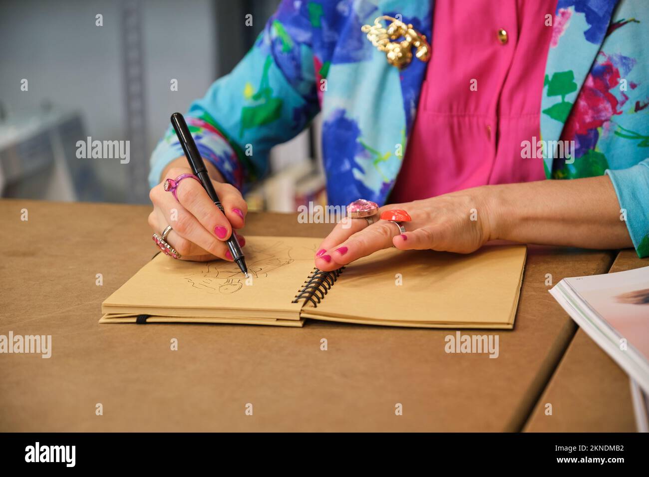 Unrecognizable dressmaker with colorfull clothes drawing new layout. Stock Photo