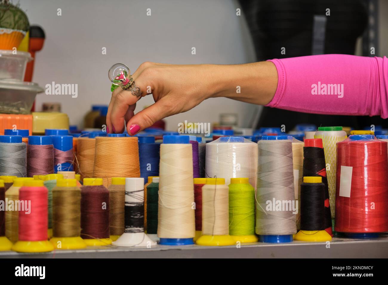 Unrecognizable dressmaker with colorfull clothes choosing a thread. Stock Photo