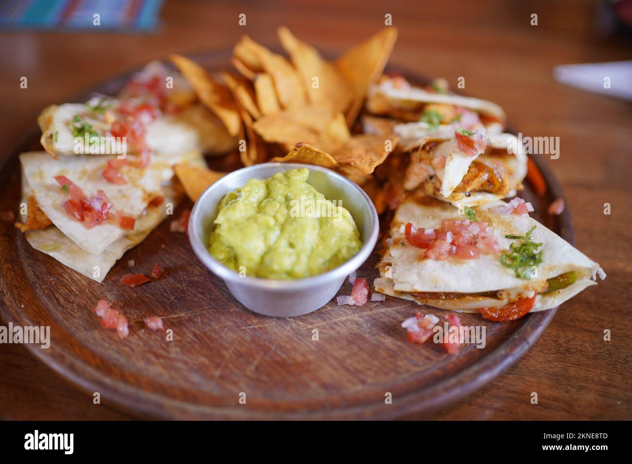 Chicken quesadilla with nachos and guacamole on a wooden plate. Stock Photo