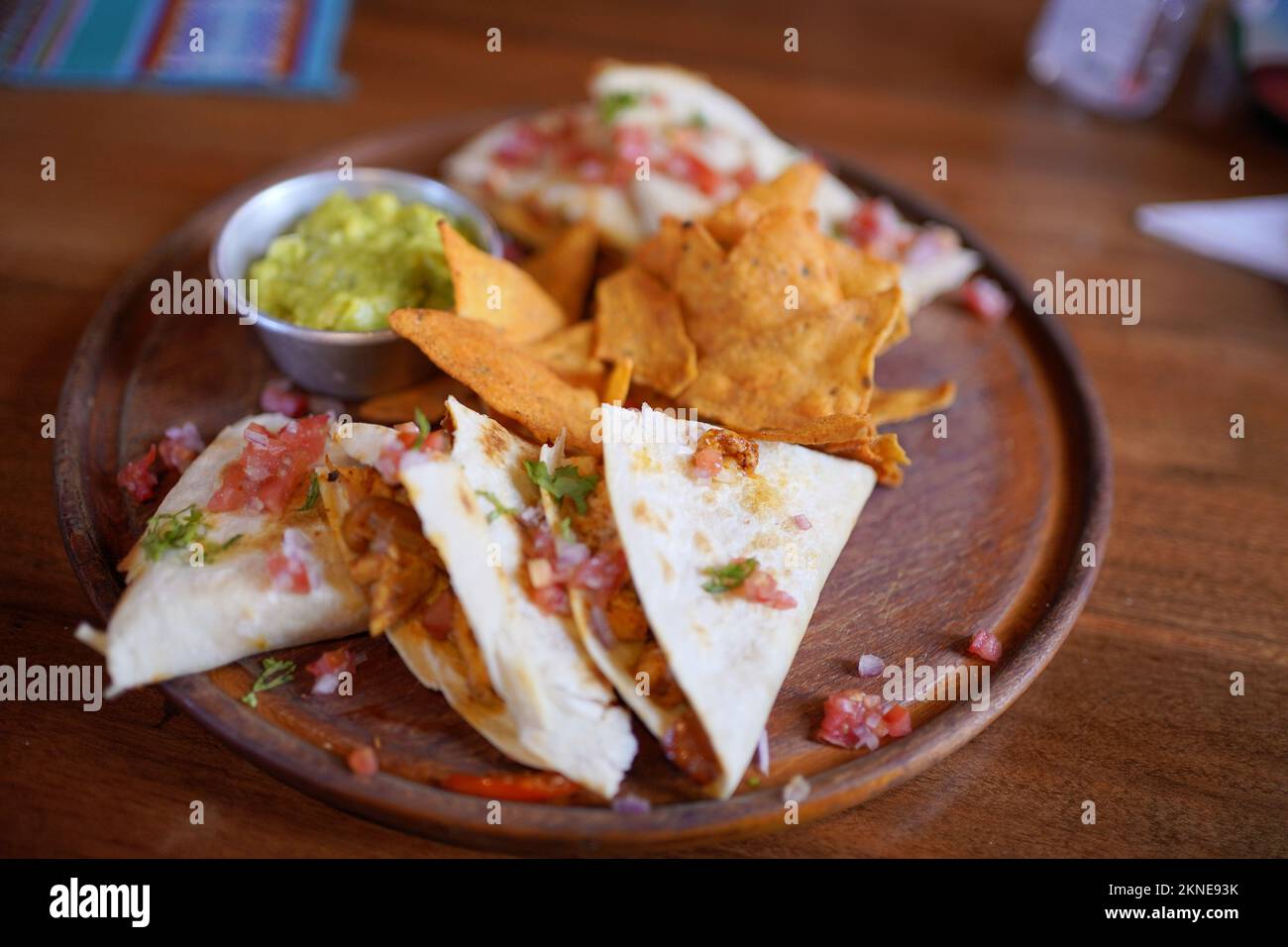 Chicken quesadilla with nachos and guacamole on a wooden plate. Stock Photo