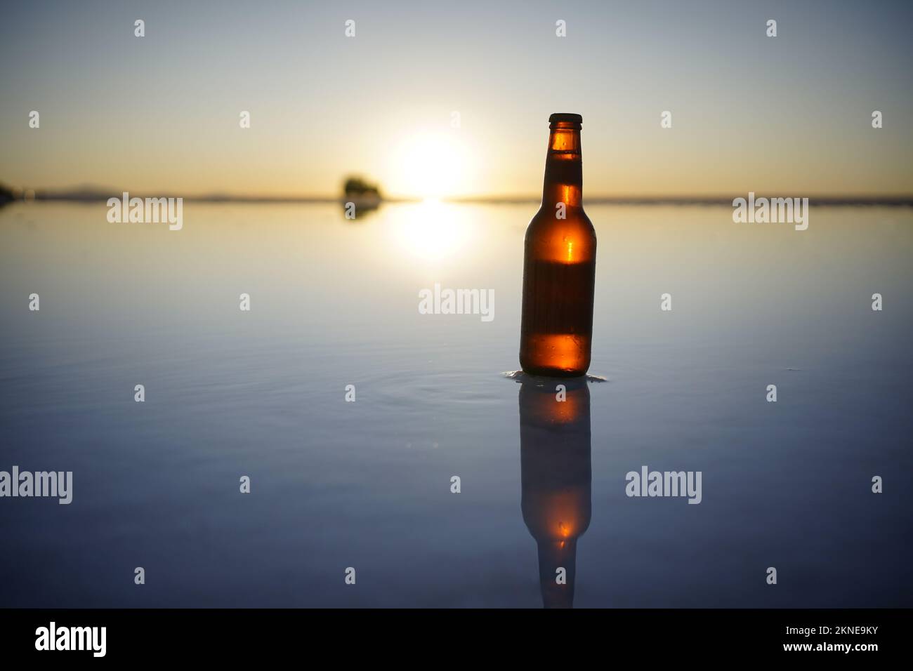 bottle of beer with reflection at sunset on Uyuni salt flats, Bolivia.Sony Alpha 7 III, 35mm. Stock Photo