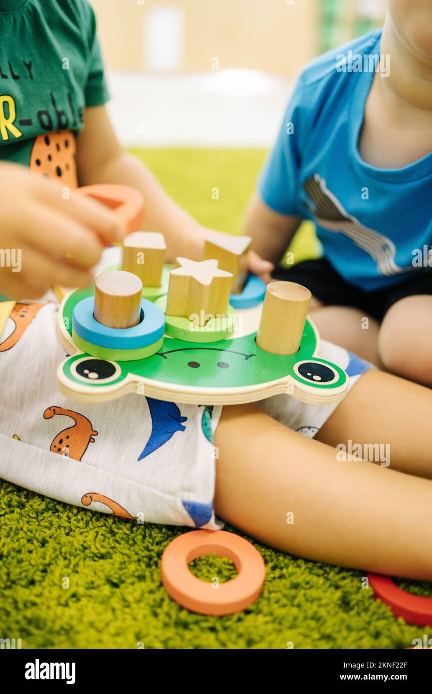 Little children play with wooden toys in kindergarden Stock Photo