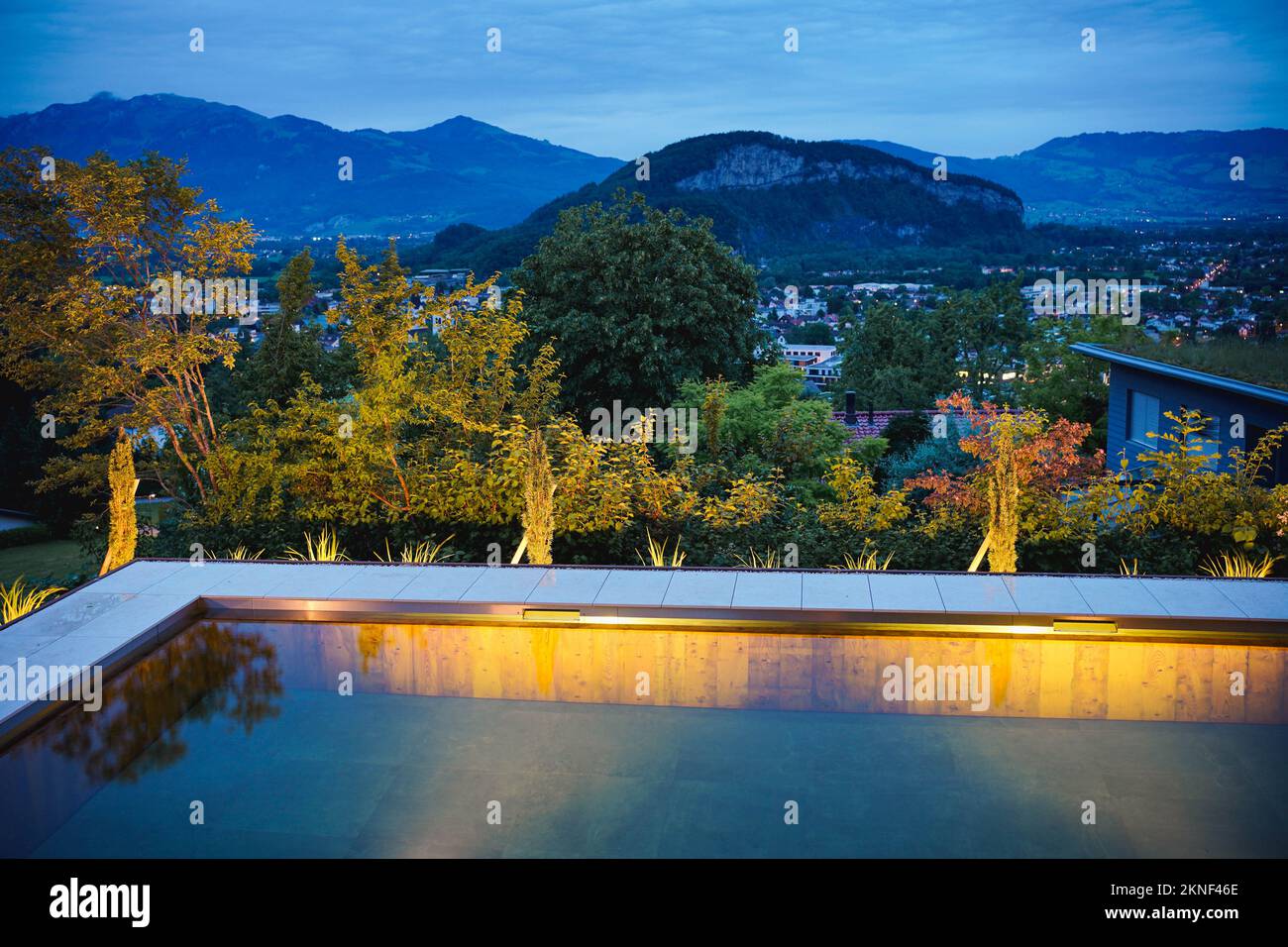 Evening view of a illuminated swimming pool with wooden walls in a ...