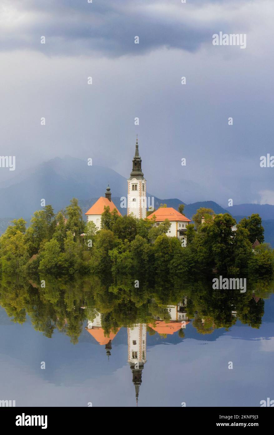 A vertical shot of the church on Bled island with its reflection on ...