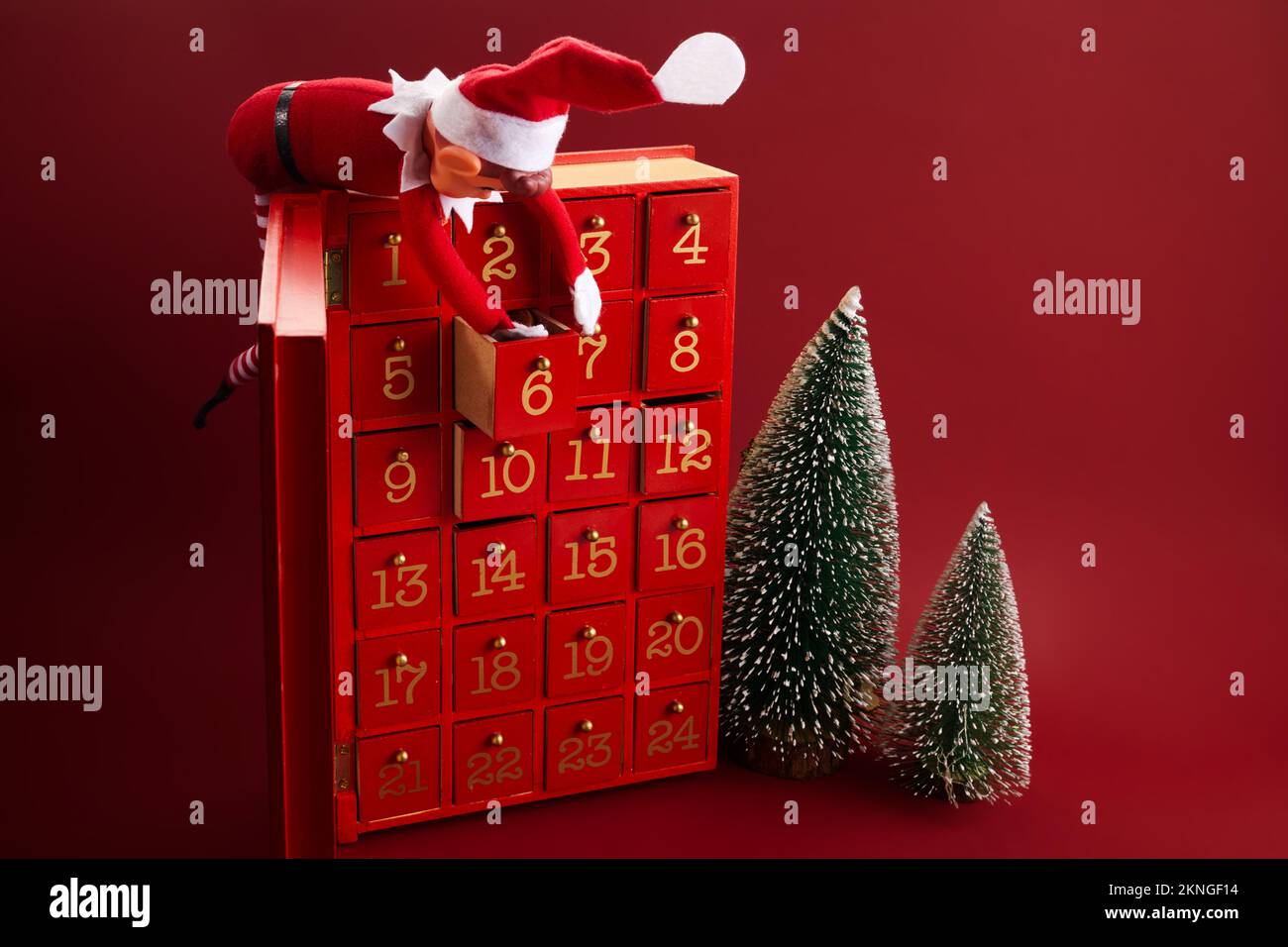 Christmas advent calendar with an elf and gifts on red background Stock