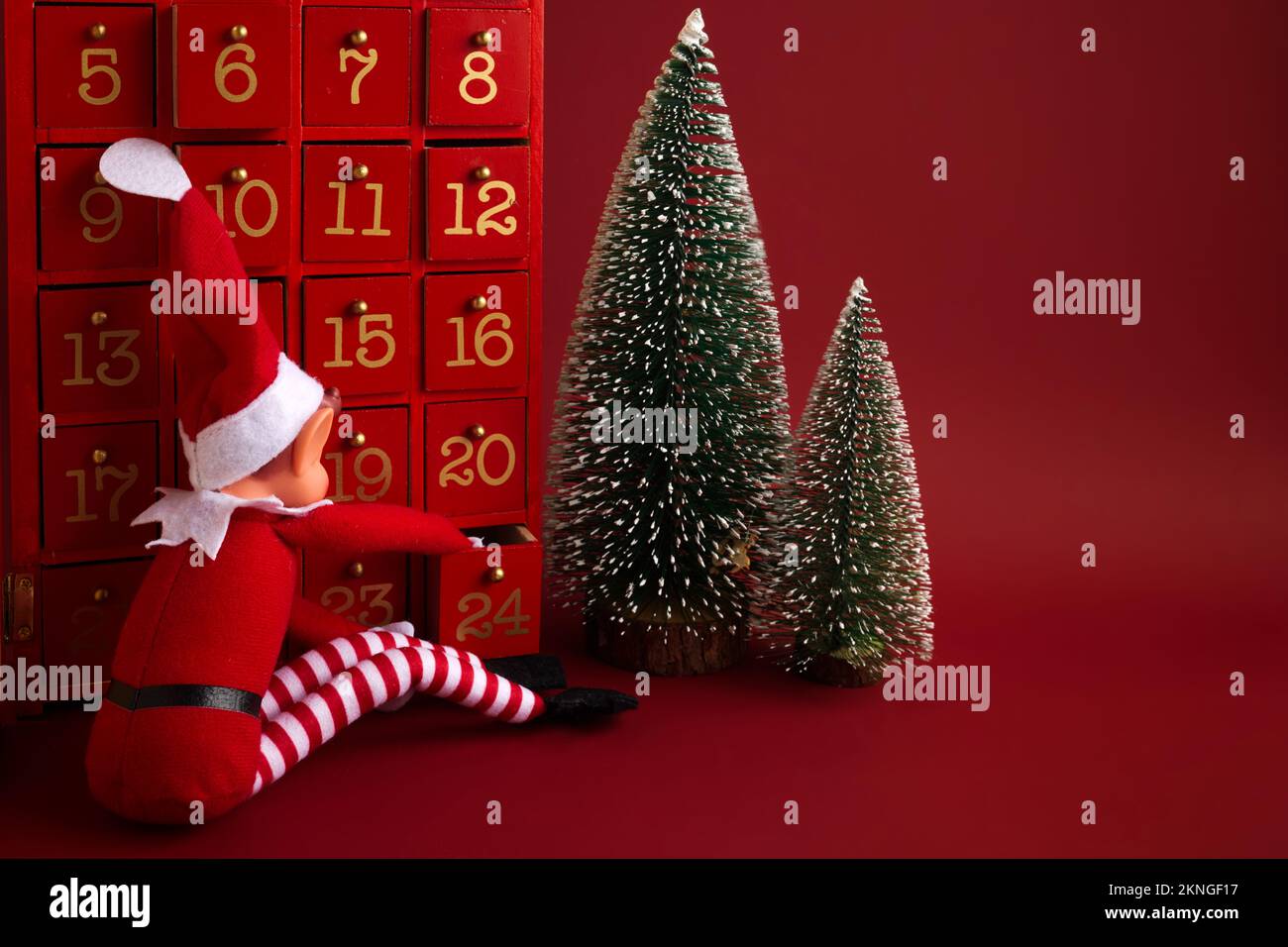 Christmas advent calendar with an elf and gifts on red background Stock
