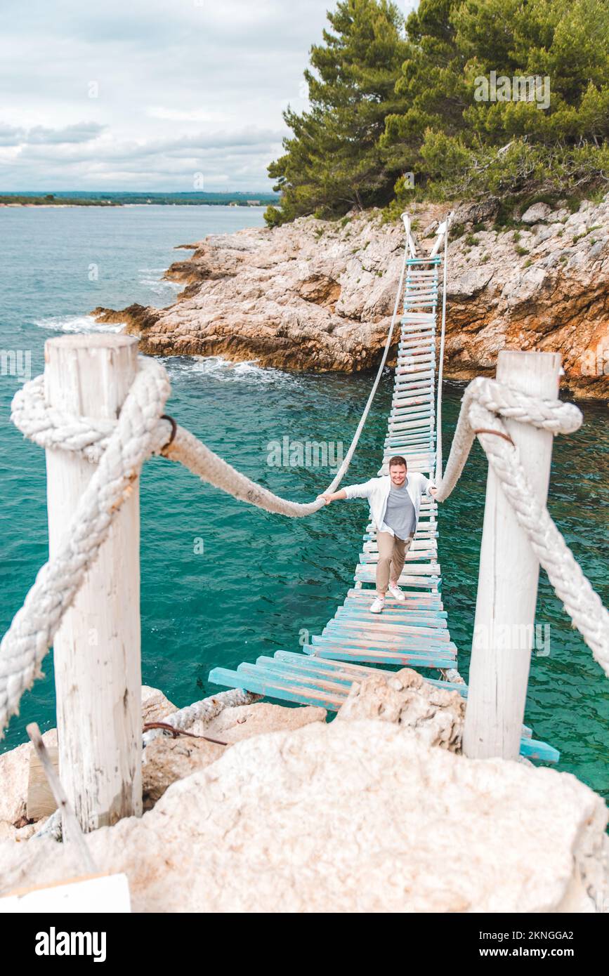 man walking by suspension bridge Stock Photo - Alamy