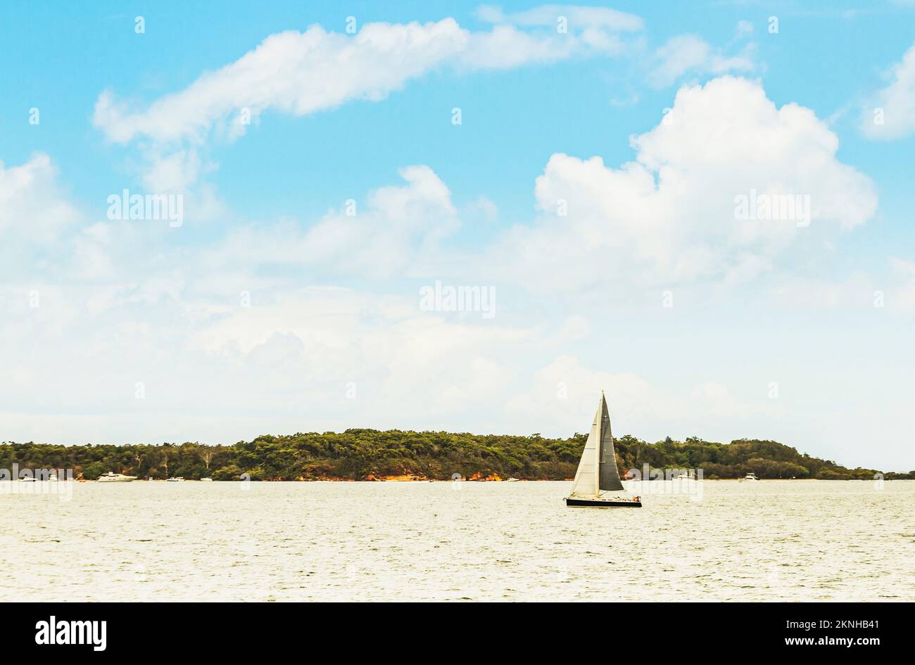 Horizontal seaside expanse of distant islands, blue cloudy skies and sail boats. Peel Island, Moreton Bay, Queensland, Australia Stock Photo
