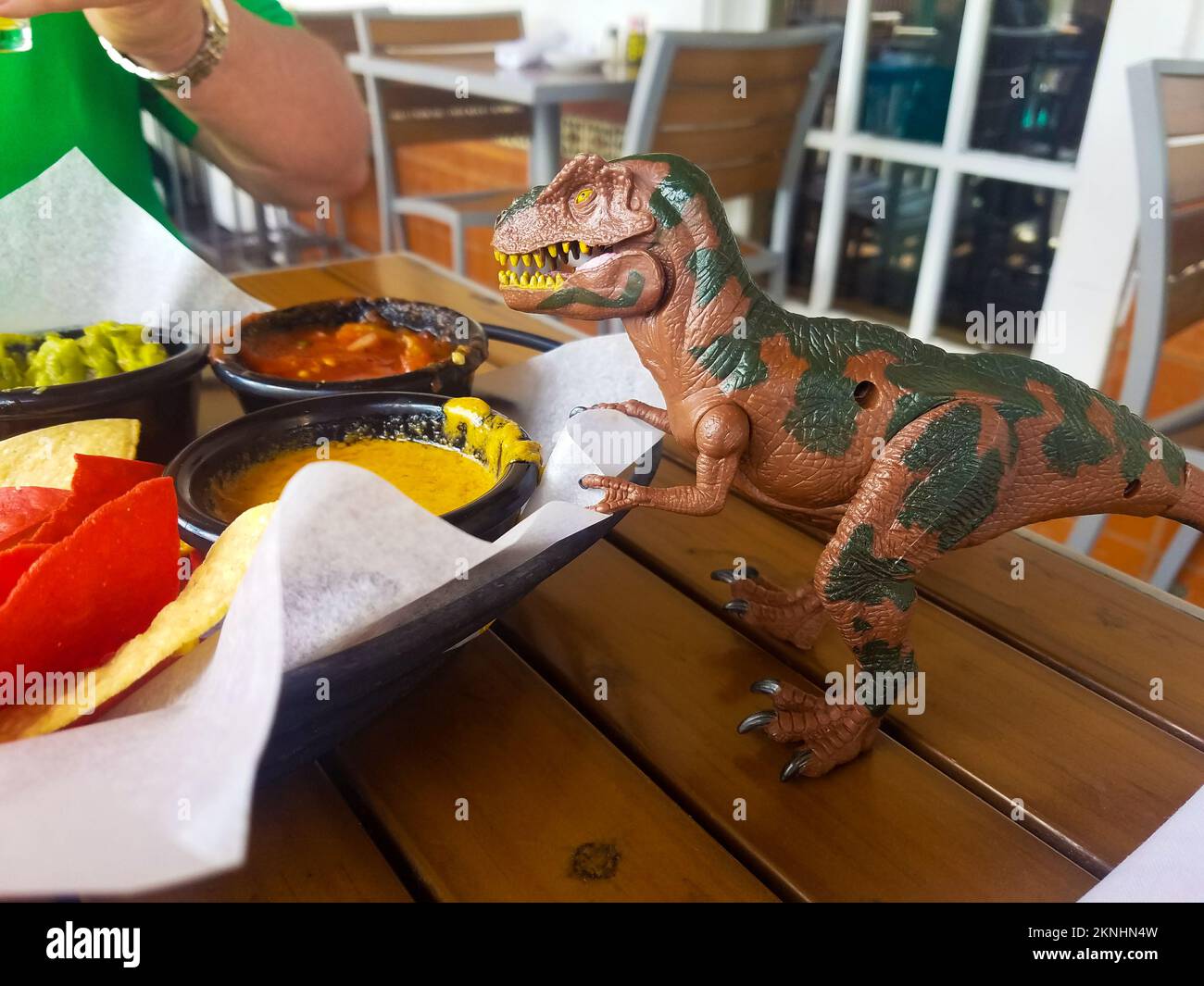 Dinosaur toy overlooks chips appetizer in Mexican resturant Stock Photo