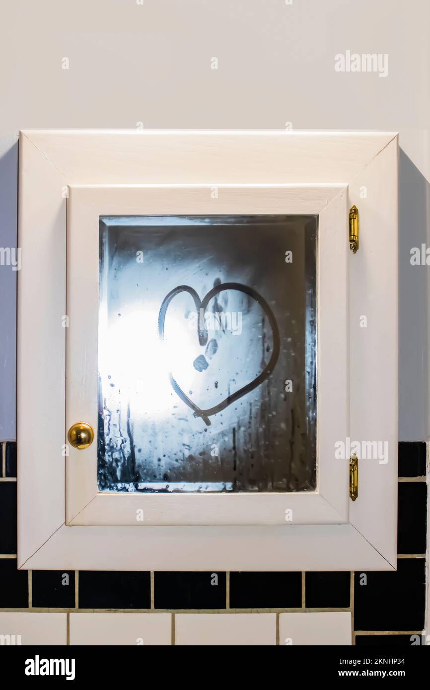 Heart drawn in steamy mirror in retro art deco bathroom with black and white tile and gold knobs Stock Photo