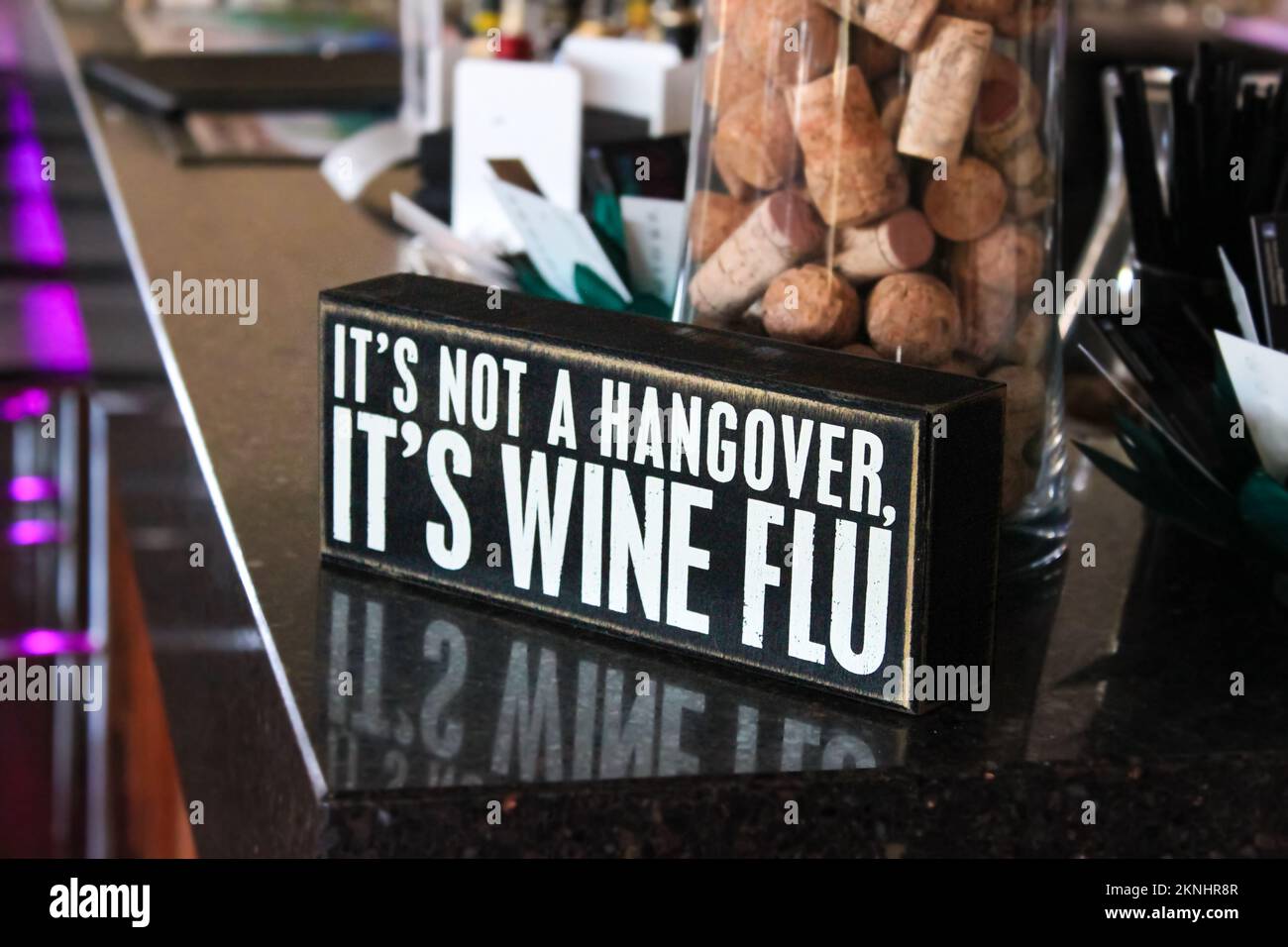 Sign saying Its not a hangover its wine flue sitting on marble countertop of bar with jar a corks behind Stock Photo