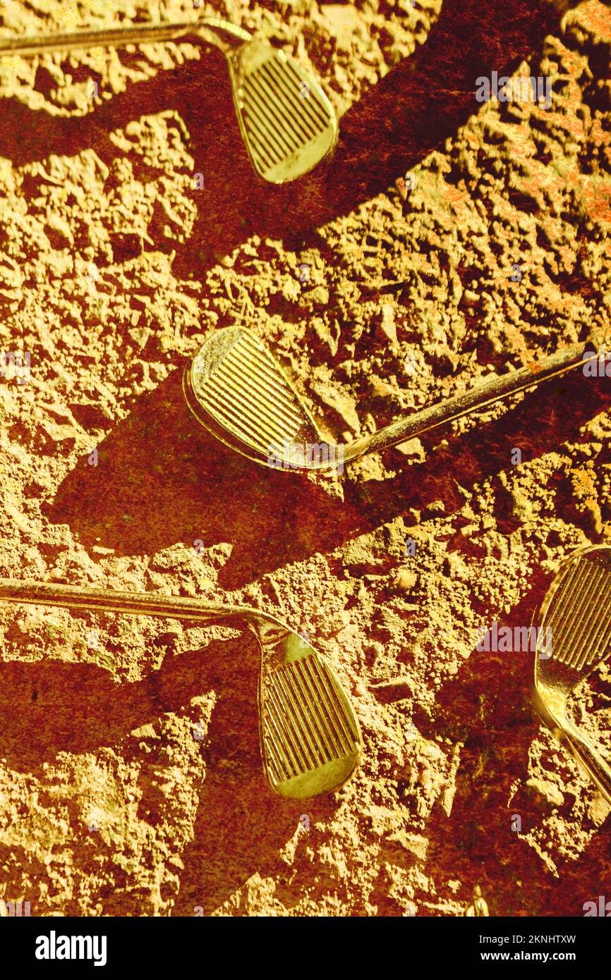 Old sports art on a group of vintage golf irons in a antique sand