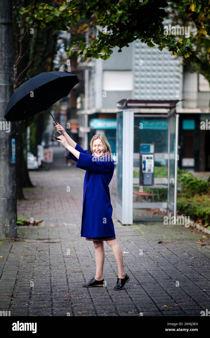 A happy woman with an umbrella is outside. Stock Photo