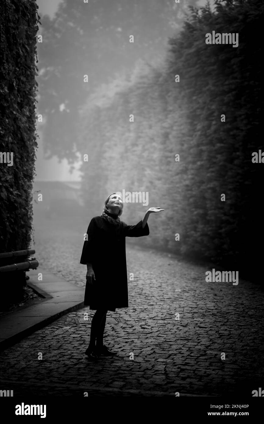 Woman in a coat, in an ancient public garden in a thick fog. Black and