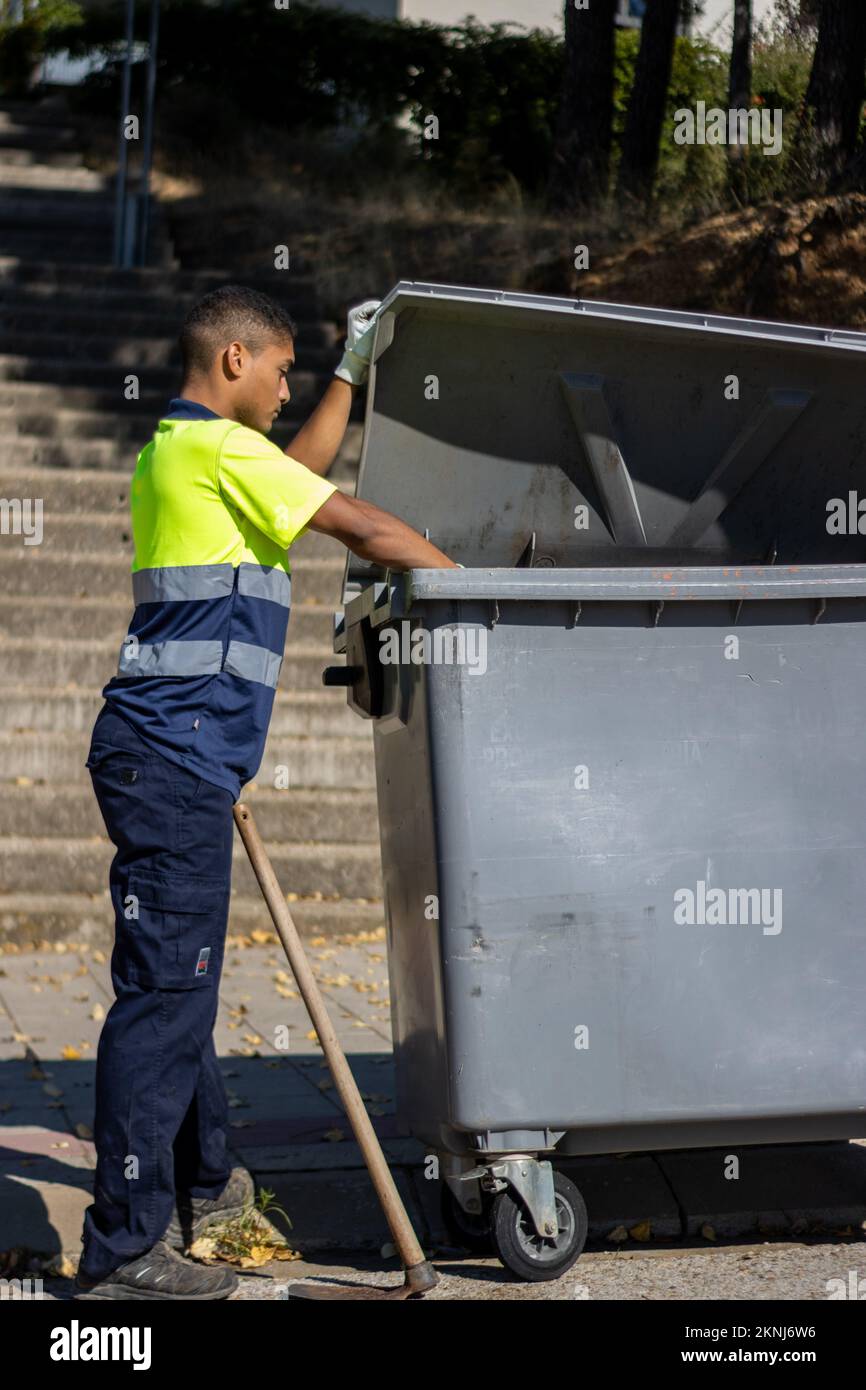 Worker throwing waste in a garbage bin hires stock photography and