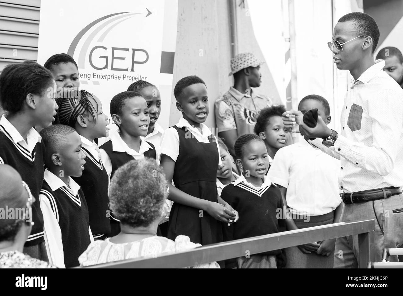 A view of African Preschool kids singing songs outside a local grocery shop in grayscale Stock Photo
