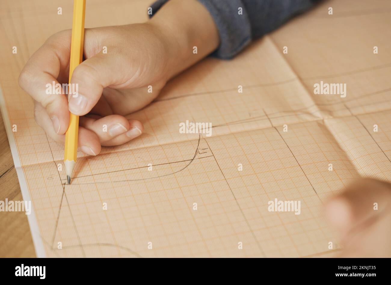 A fashion designer draws a sketch of a clothing collection on graph ...