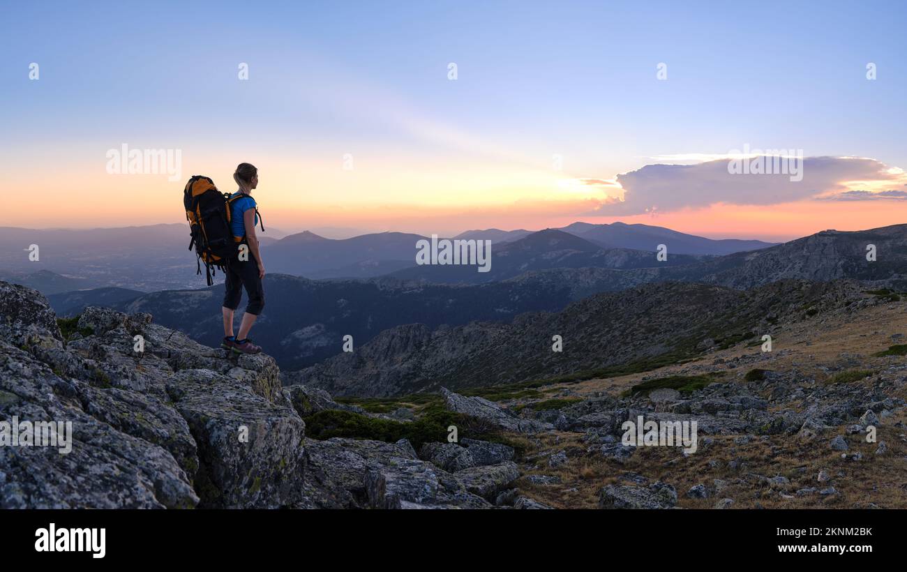 Woman hiker watching sunset on top of the mountain peak Stock Photo