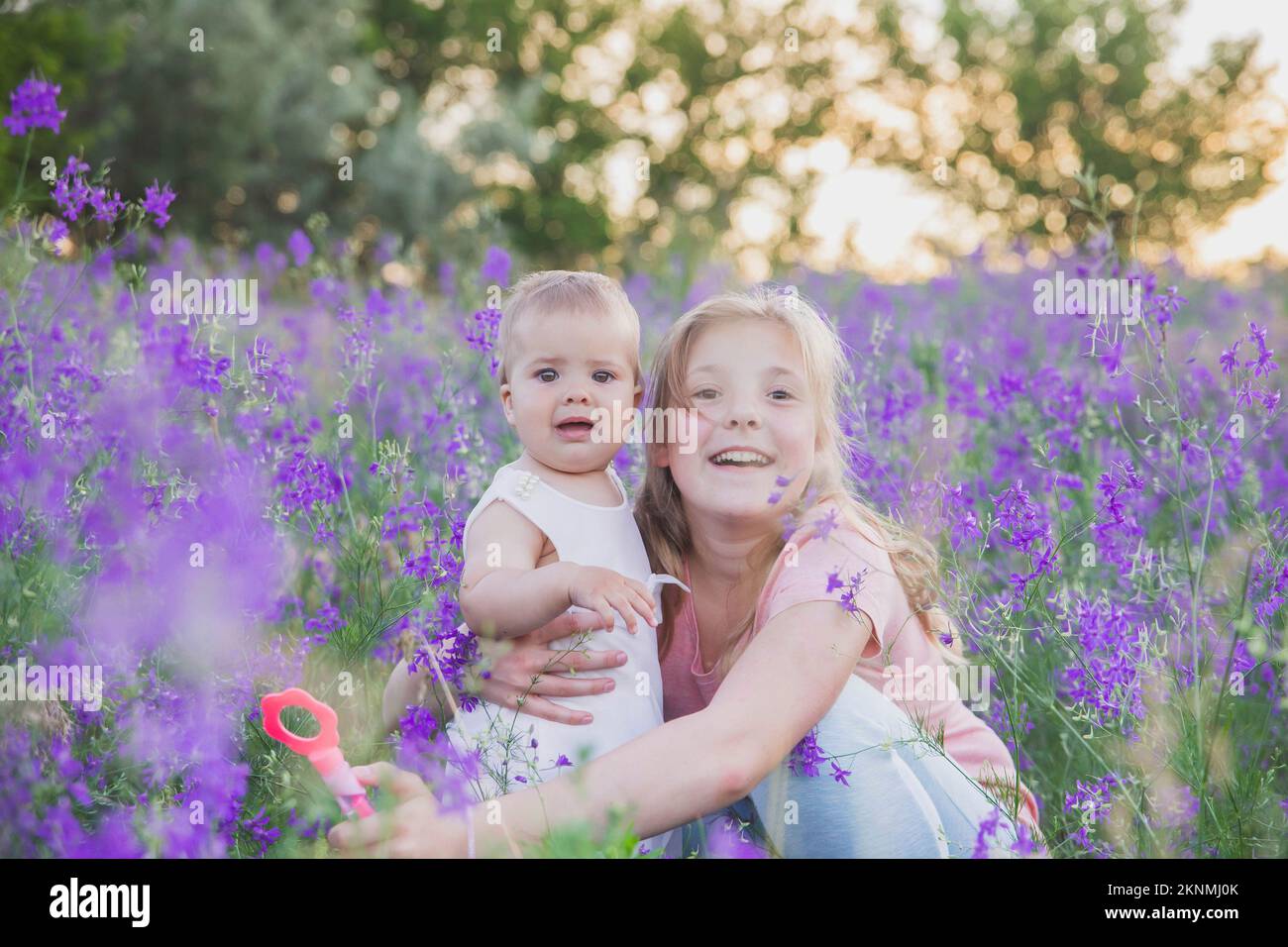 Two blond sisters in flowers at sunset Stock Photo Alamy