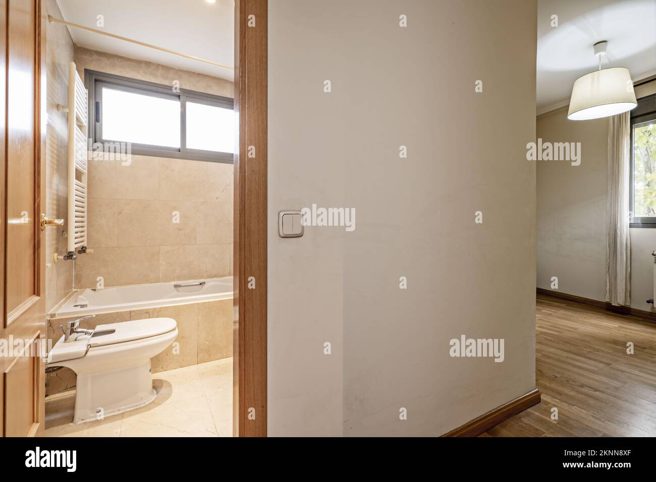 Empty double bedroom with full bathroom en suite with marble tiling and French oak parquet flooring in the room Stock Photo