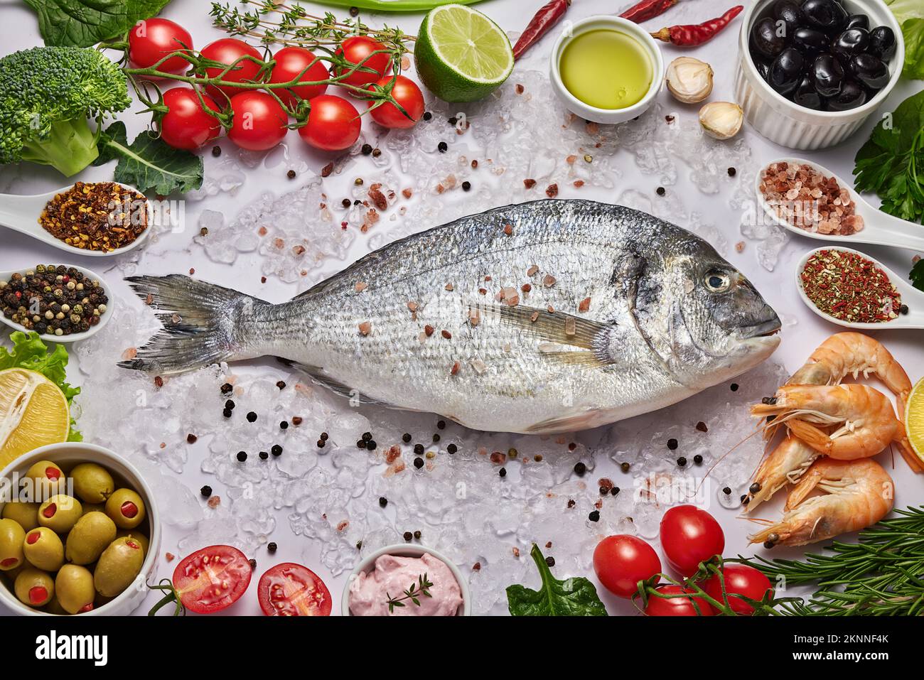 Fresh Fish Food background. Different seafood, shrimps and red caviar. Fish for cooking with herbs, vegetables and spices isolated on white background Stock Photo