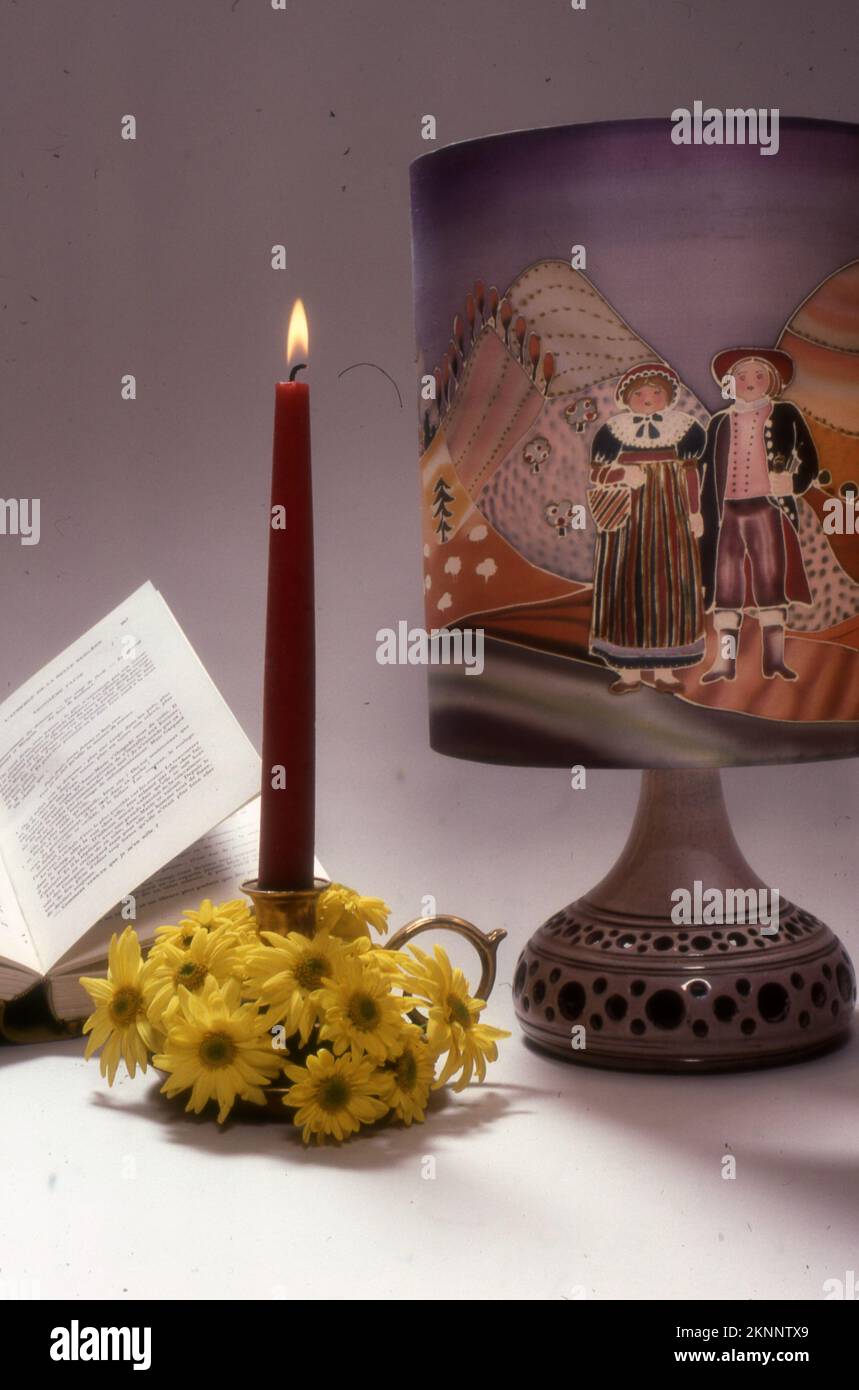 A beautiful view of a candlestick with an open book next to a lit candle on a table Stock Photo