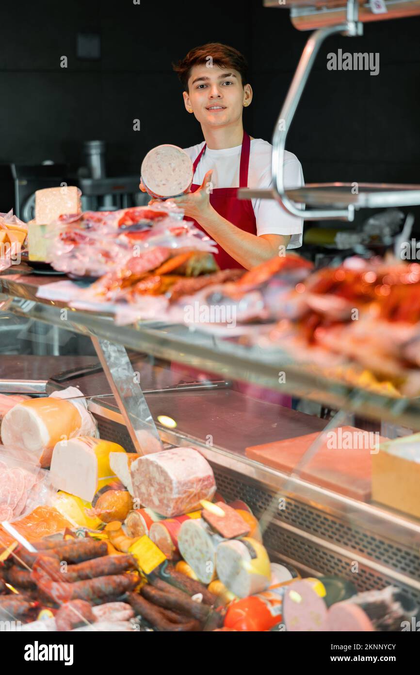 Young salesman offering traditional spanish mortadella in grocery store